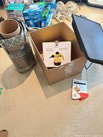 Lot overview showing boxed steam cleaner inside cardboard box, rolled ProElite floor mat and black TV tray top