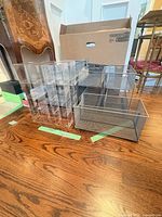 Group of acrylic and metal mesh organizers on floor