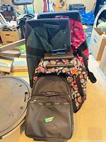 Multiple bags including black backpack, wheeled trolley, patterned totes, small pouch