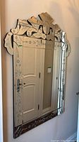 Front view of Venetian etched glass mirror hanging on wall