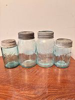 Four mason jars front view on wood surface