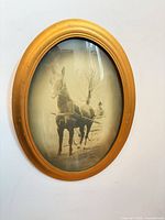 Front view showing gold oval frame, convex glass, sepia horse photo
