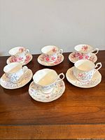 Six assorted Royal Albert teacup & saucer sets on wooden table