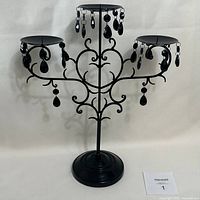 Full view of three-arm black metal candelabra on stand