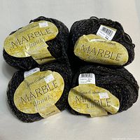 Four balls of James C Brett Marble Chunky yarn with labels visible