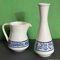 Creamer left, vase right, frontal view showing blue floral band