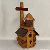 front angled view showing log body, roof, steeple, entry hole and front cross