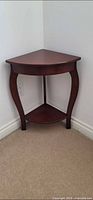 Triangular dark brown corner table with lower shelf and curved legs