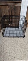 overall view of black metal wire dog crate with grey cushion inside