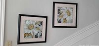Both framed floral prints hung on wall