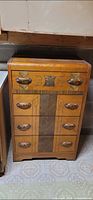Front view of vintage wooden dresser showing four drawers and decorative veneer