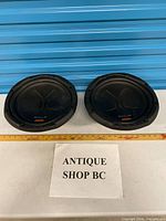 Both subwoofers side-by-side with tape measure for scale