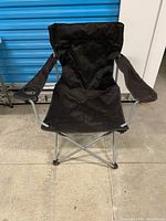 Front view of black folding camping chair showing fabric seat, armrests, and frame