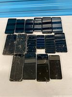 All 18 phones arranged face-up showing varying sizes and damage