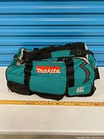 Full view of Makita teal and black contractor bag with ruler for scale