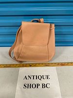 Front view of beige faux leather backpack with ruler for scale