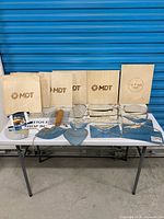 Overall view of six wooden logo boards and assorted galvanized plaques on table