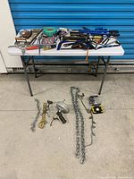 Overall view of table with assorted hand tools and chains on floor