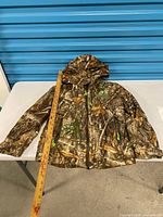 Front view of Realtree youth camo insulated jacket with hood, ruler for scale