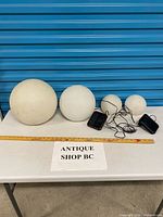 Group shot of four globes, two solar panels, measuring tape for scale