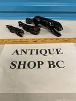 All three black ceramic panther figurines with ruler for scale