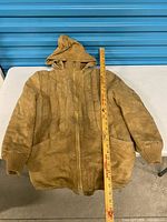 Front view of tan leather hooded jacket with zipper and yardstick showing 32-inch length