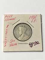 Obverse view of coin in cardboard 2x2 holder marked Fiji Islands 1 Shilling .500 Silver VF 1935
