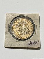 Coin in cardboard flip showing obverse through plastic