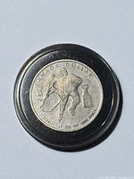 Front view of coin in holder showing hockey player and Stanley Cup design