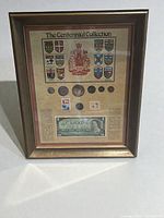 Front view of framed Centennial Collection showing coins, stamps, banknote and crests