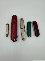Five folding knives lined up showing handle colors and sizes