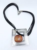 Full necklace showing square silver pendant, amber cabochon, multi-strand cord, clasp visible