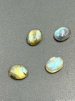 four oval labradorite cabochons on dark surface