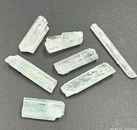 Seven pale icy-blue raw crystal prisms on dark background