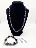 Entire three-piece jewelry set displayed on bust and surface