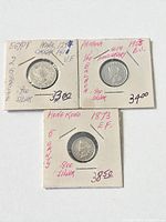 Obverse sides of three silver coins in holders with handwritten details