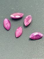 Five marquise-cut rubies on dark surface