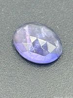 Top view of oval rose-cut sapphire showing facets and color