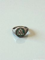 Front view of sterling silver signet ring showing green enamel face and text