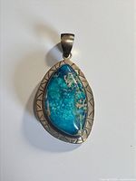 Front view of sterling silver pendant showing blue jasper cabochon and etched border