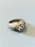 angled view of sterling silver ring showing bezel-set clear stone