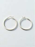 Both hoop earrings displayed flat, showing overall shape and clasp style