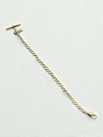 Full view of entire pocket watch chain laid flat showing T-bar, curb links, and swivel clasp