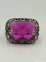 Front view showing magenta faceted stone and floral bezel