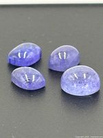 Four tanzanite cabochons on dark background
