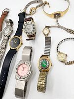 Nine assembled wristwatches laid out showing variety of styles, dials and straps