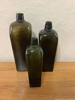 Front view of the three loden green bottles showing relative sizes and shape