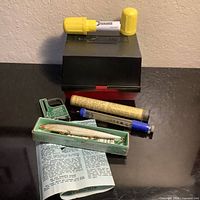 Overall group view showing reel box, snake bite kit, Langley De-Liar, Depth-O-Plug and Rapala lure