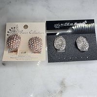 Two pairs of clip-on earrings on retail cards, showing design and condition