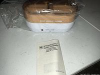 Cleaner wrapped in plastic with manual in foreground